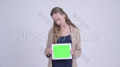 年轻的年轻孕妇一边思考一边展示数码平板电脑